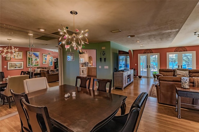 dining space featuring light hardwood / wood-style flooring, french doors, and a notable chandelier