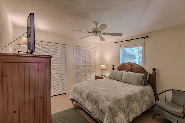 bedroom with ceiling fan, two closets, and light hardwood / wood-style floors