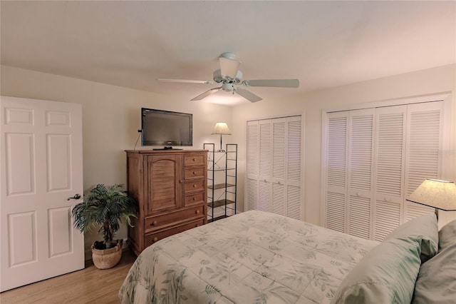 bedroom with ceiling fan, light wood-type flooring, and two closets