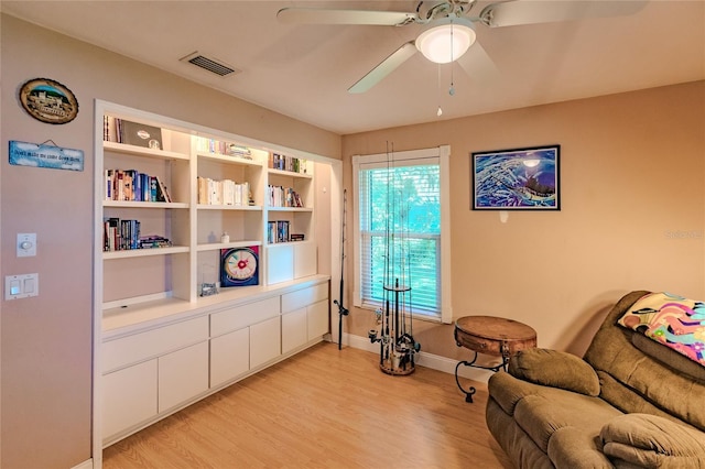 sitting room featuring ceiling fan, light hardwood / wood-style floors, and built in shelves