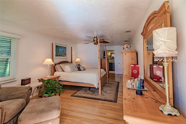 bedroom with ceiling fan, a textured ceiling, and light hardwood / wood-style flooring