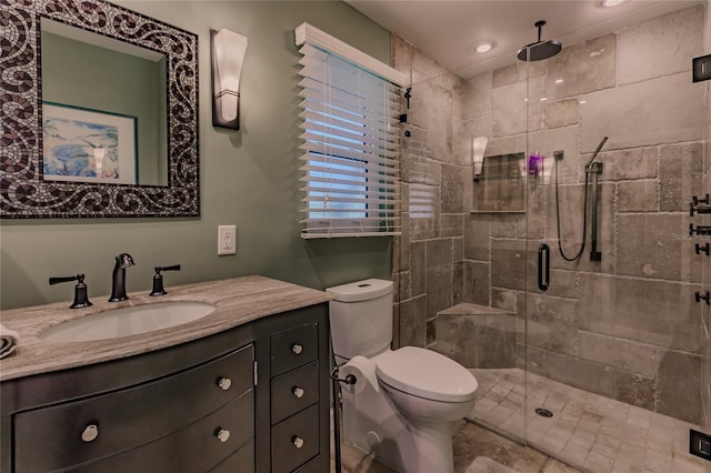 bathroom featuring toilet, a shower with shower door, and vanity