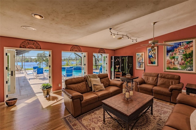 living room featuring vaulted ceiling, ceiling fan, track lighting, and wood-type flooring