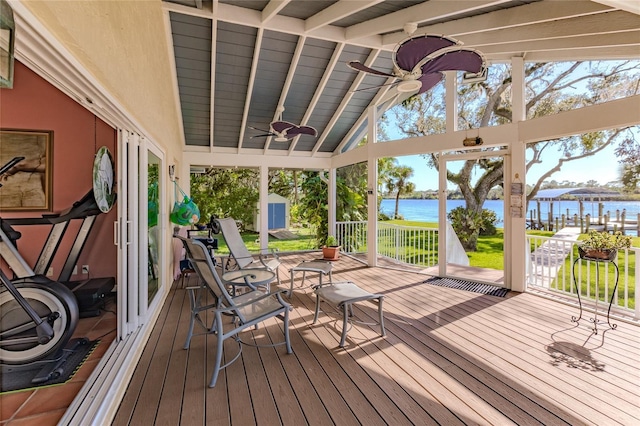 wooden deck with ceiling fan, a storage shed, and a water view