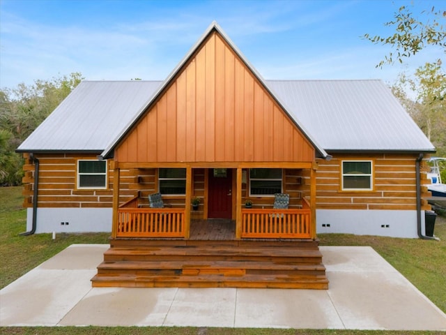 log cabin with covered porch and a front lawn