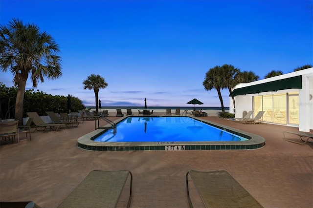 pool at dusk featuring a patio