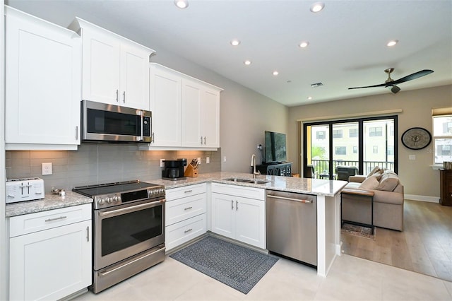 kitchen featuring kitchen peninsula, appliances with stainless steel finishes, sink, and white cabinetry