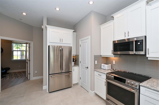 kitchen featuring tasteful backsplash, light tile patterned flooring, light stone countertops, stainless steel appliances, and white cabinets