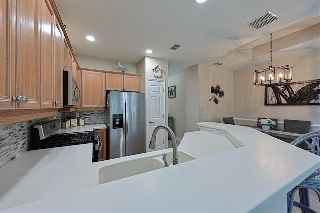 kitchen featuring hanging light fixtures, stainless steel appliances, a notable chandelier, a kitchen bar, and sink