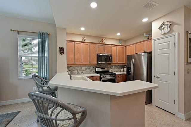 kitchen featuring a kitchen breakfast bar, stainless steel appliances, kitchen peninsula, sink, and light tile patterned flooring