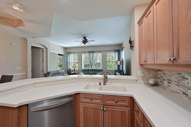 kitchen with sink, ceiling fan, kitchen peninsula, stainless steel dishwasher, and decorative backsplash