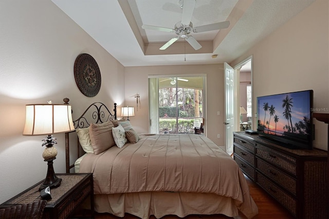 bedroom featuring hardwood / wood-style floors, a raised ceiling, ceiling fan, and access to outside