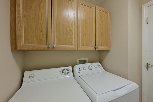 laundry room featuring washer and dryer and cabinets