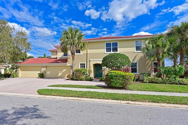 view of front of house featuring a tiled roof, decorative driveway, a garage, and stucco siding