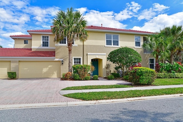 view of front of property featuring stucco siding, decorative driveway, a garage, and a tiled roof