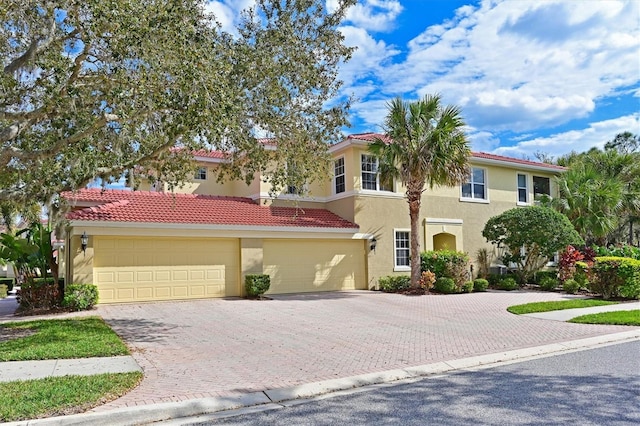 view of front of home featuring stucco siding, a tile roof, decorative driveway, and a garage