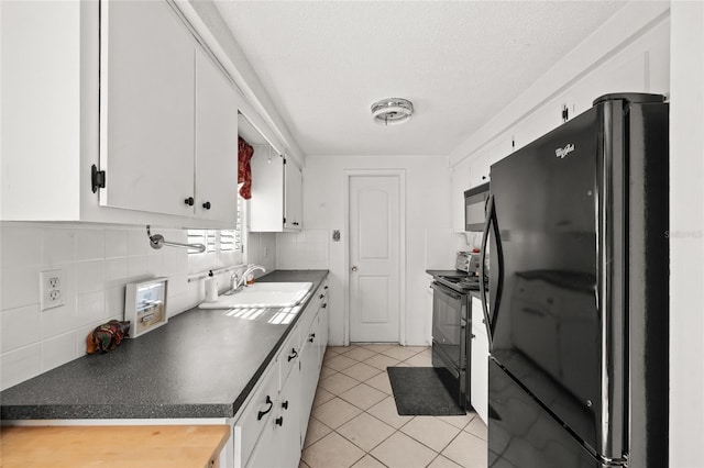 kitchen featuring sink, black appliances, light tile patterned floors, decorative backsplash, and white cabinets