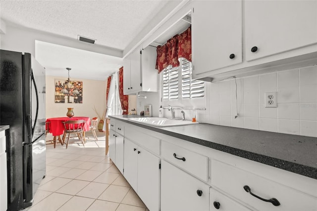 kitchen with sink, white cabinetry, a textured ceiling, black refrigerator, and backsplash