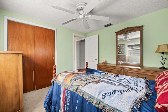 carpeted bedroom featuring ceiling fan, a closet, and a textured ceiling