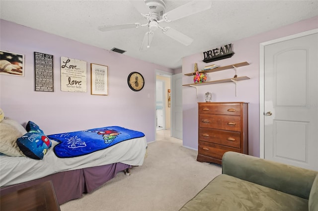 bedroom featuring ceiling fan, light carpet, and a textured ceiling