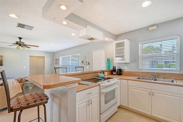 kitchen with sink, a kitchen breakfast bar, white electric stove, and kitchen peninsula