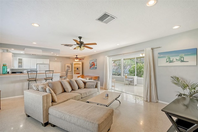 living room with a textured ceiling and ceiling fan