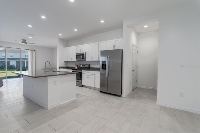 kitchen featuring stainless steel appliances, an island with sink, ceiling fan, white cabinets, and sink