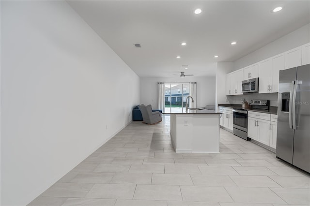 kitchen featuring white cabinets, ceiling fan, an island with sink, and appliances with stainless steel finishes