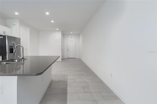 kitchen with sink, white cabinetry, kitchen peninsula, a breakfast bar area, and stainless steel fridge with ice dispenser