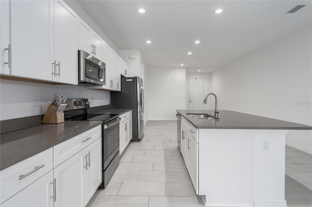 kitchen featuring stainless steel appliances, sink, white cabinets, light tile patterned floors, and a center island with sink