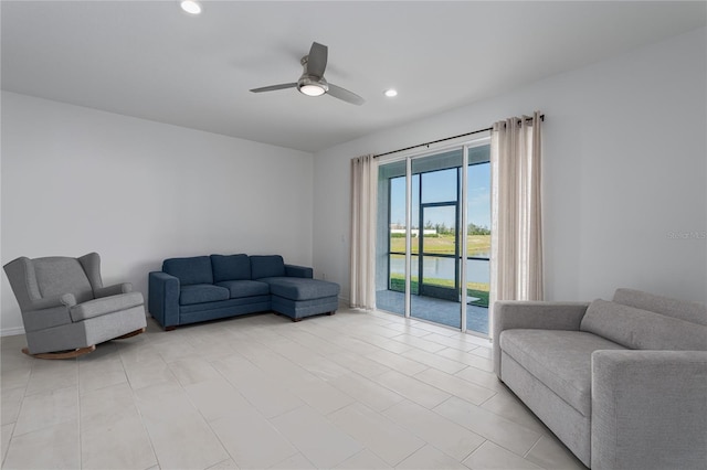 living room featuring ceiling fan and a water view