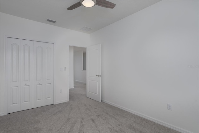 unfurnished bedroom featuring ceiling fan, a closet, and light carpet