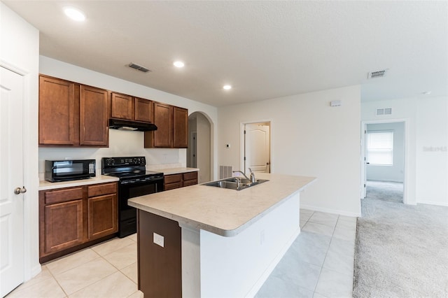 kitchen featuring sink, a center island with sink, light carpet, and black appliances