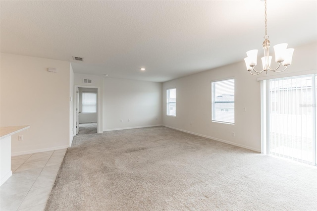 carpeted empty room featuring an inviting chandelier