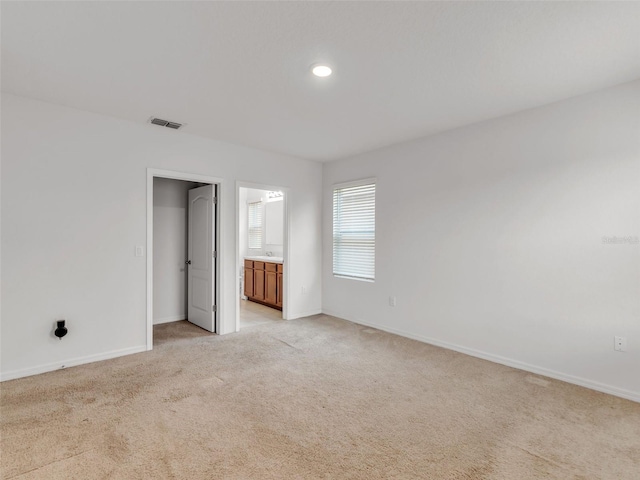 unfurnished bedroom with ensuite bath and light carpet