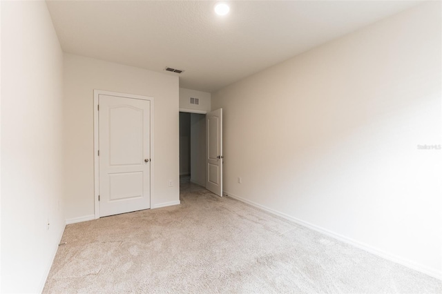 unfurnished bedroom with a closet and light colored carpet