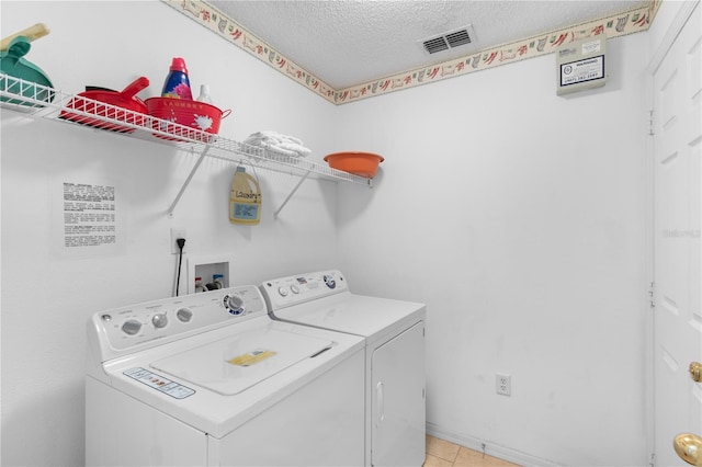 laundry area with light tile patterned floors, washer and dryer, and a textured ceiling