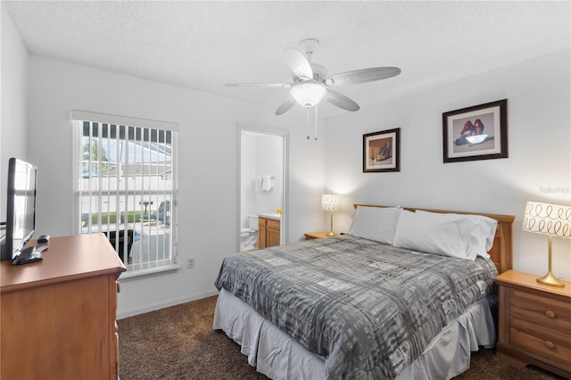 bedroom featuring a textured ceiling, ceiling fan, dark carpet, and ensuite bath