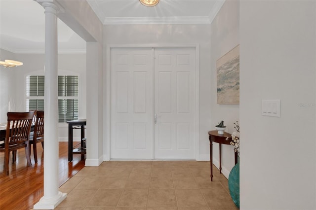 tiled foyer featuring decorative columns and crown molding