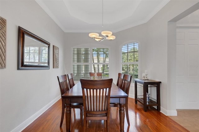 dining space featuring hardwood / wood-style flooring, a tray ceiling, a chandelier, and ornamental molding