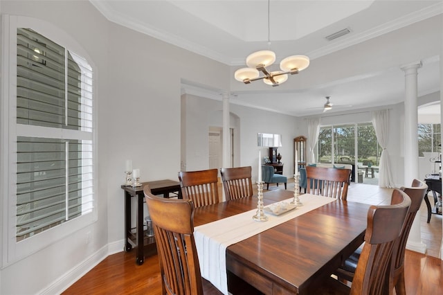 dining room with ceiling fan with notable chandelier, hardwood / wood-style floors, ornamental molding, and ornate columns