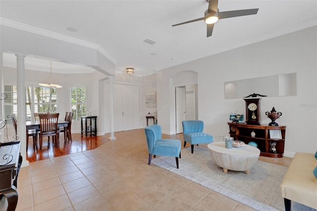 living room featuring ceiling fan, light tile patterned floors, crown molding, and decorative columns