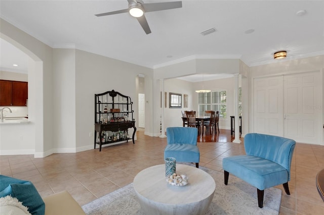 living room with ceiling fan, sink, ornamental molding, and light tile patterned flooring