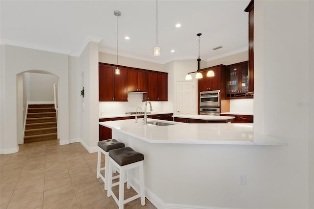 kitchen featuring light tile patterned floors, a kitchen breakfast bar, hanging light fixtures, crown molding, and sink