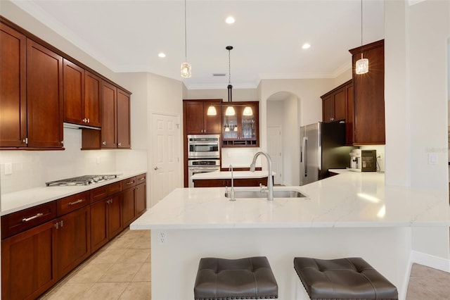 kitchen featuring a kitchen bar, sink, hanging light fixtures, stainless steel appliances, and ornamental molding