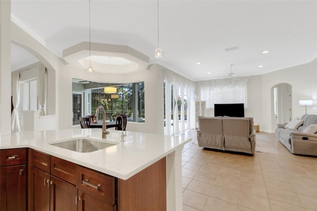 kitchen featuring ceiling fan, light tile patterned flooring, hanging light fixtures, light stone counters, and sink