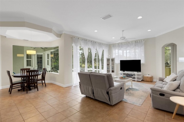 tiled living room with ceiling fan and ornamental molding