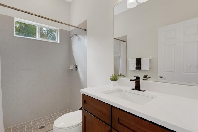 bathroom with toilet, vanity, and a tile shower