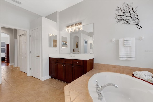 bathroom with tiled bath, tile patterned flooring, and vanity