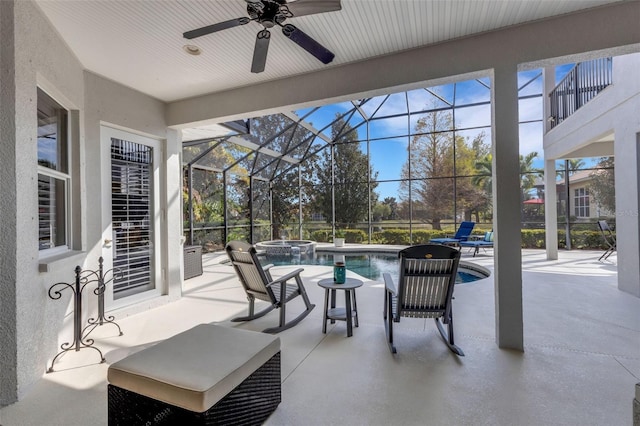 view of patio / terrace featuring ceiling fan, a swimming pool with hot tub, and a balcony